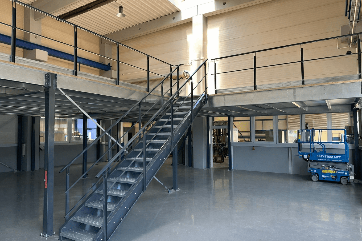 Maverlo Lagerbühne mit integrierter Treppe und Geländer gemäß Sicherheitsstandards für Industriehallen.